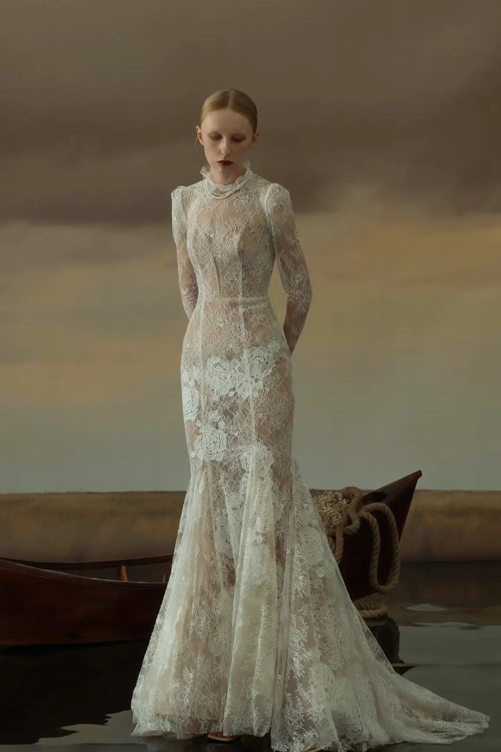 Vue de face d'une robe de mariée sirène vintage en dentelle fine avec manches longues et col montant.