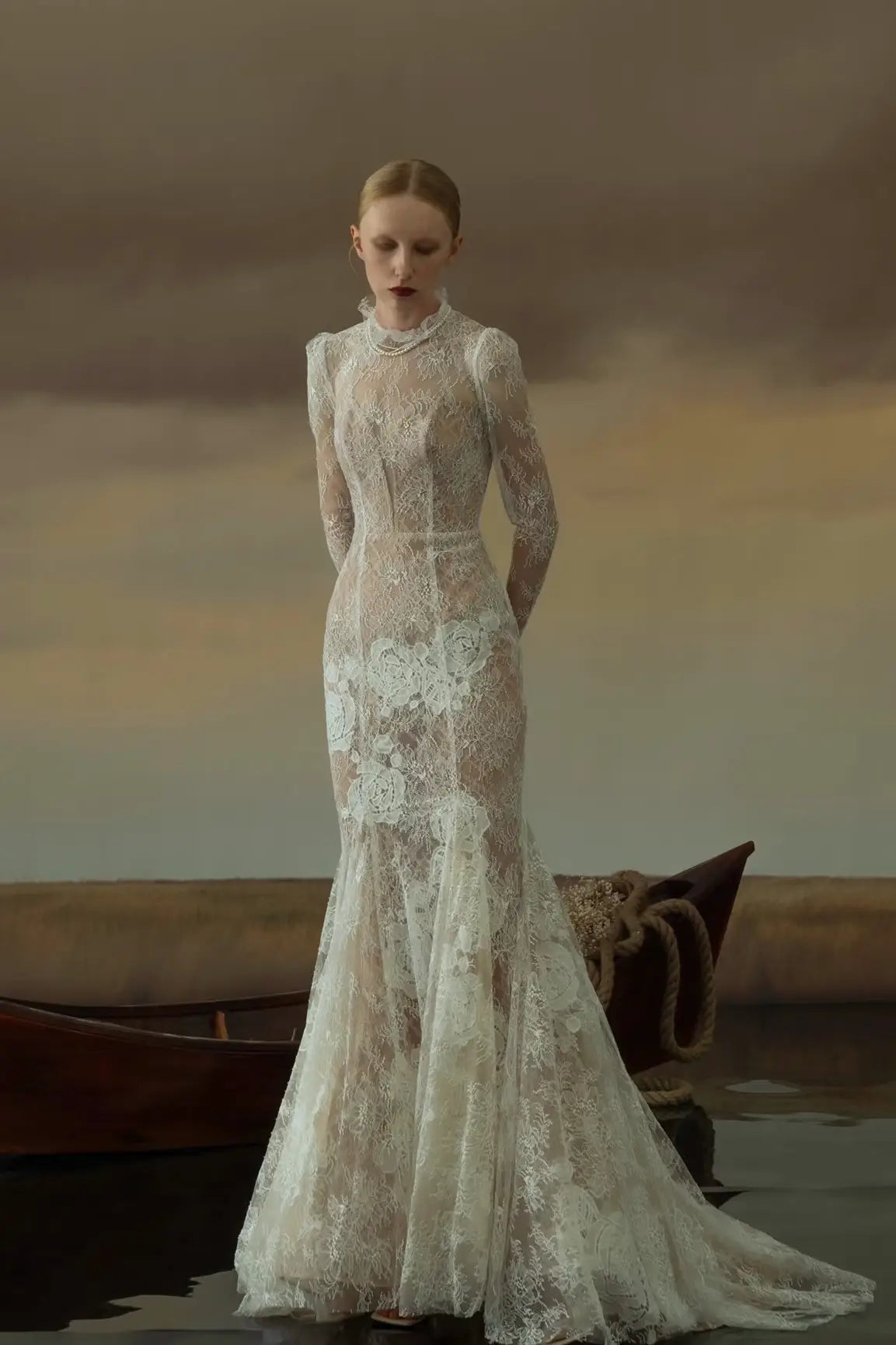 Vue de face d'une robe de mariée sirène vintage en dentelle fine avec manches longues et col montant.