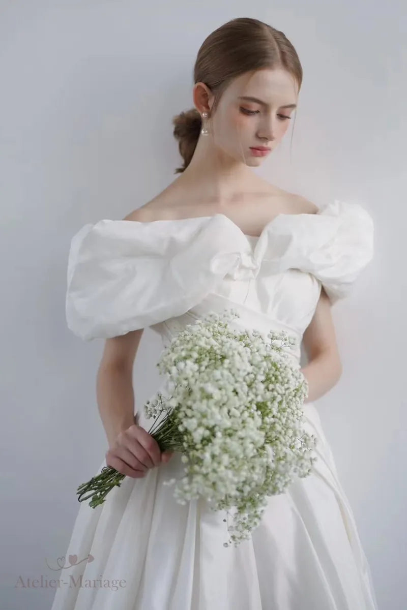 Mariée portant une robe en soie taffetas à épaules dénudées, tête baissée
