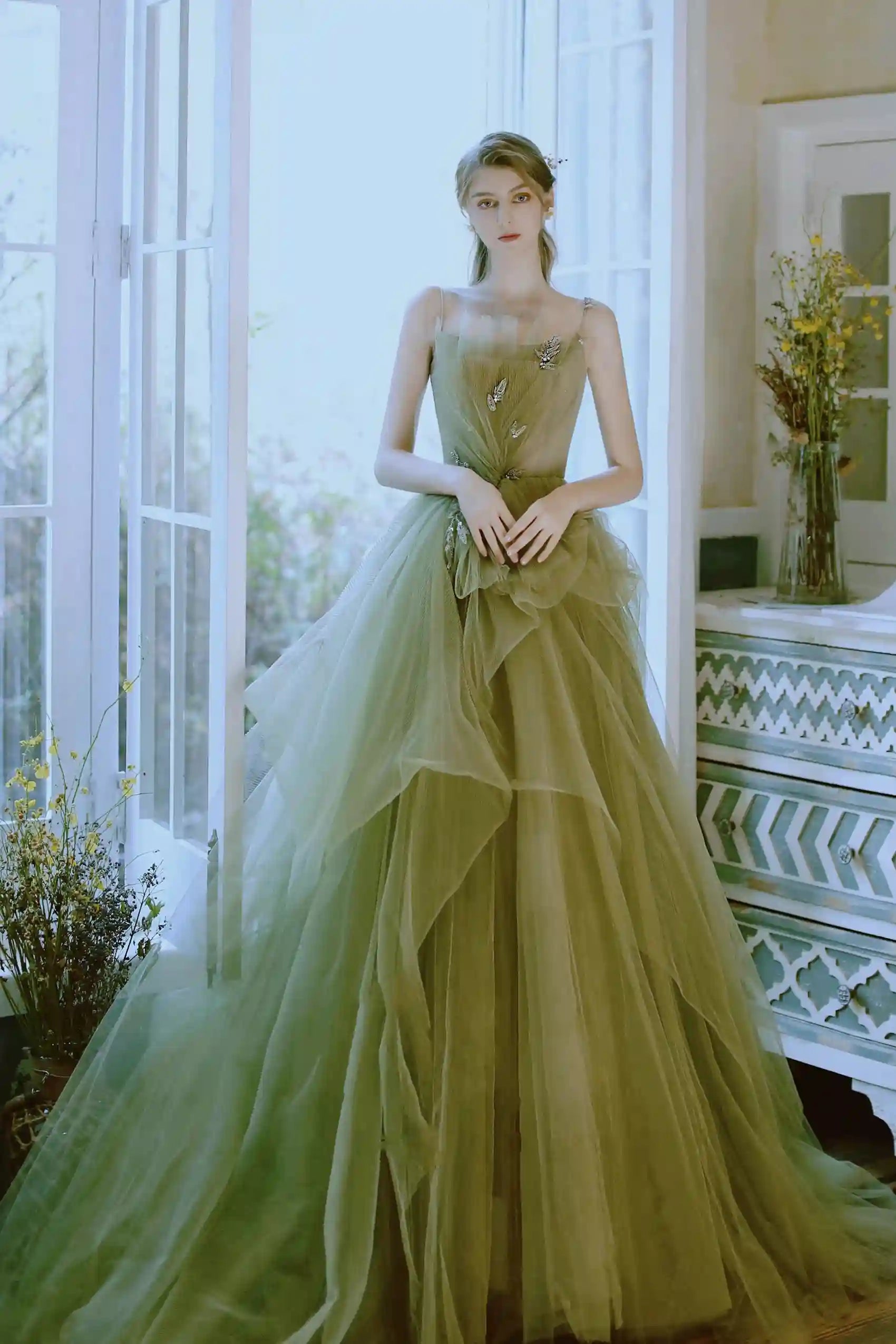 Mariée de face portant une robe de mariée vert sauge coupe princesse en tulle avec corsage plissé et détails floraux.