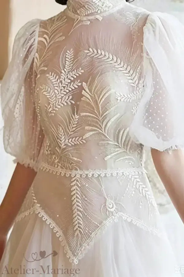 Buste d'une robe de mariée vintage montrant les manches bouffantes en tulle plumetis et les finitions minutieuses de l'Atelier Mariage.
