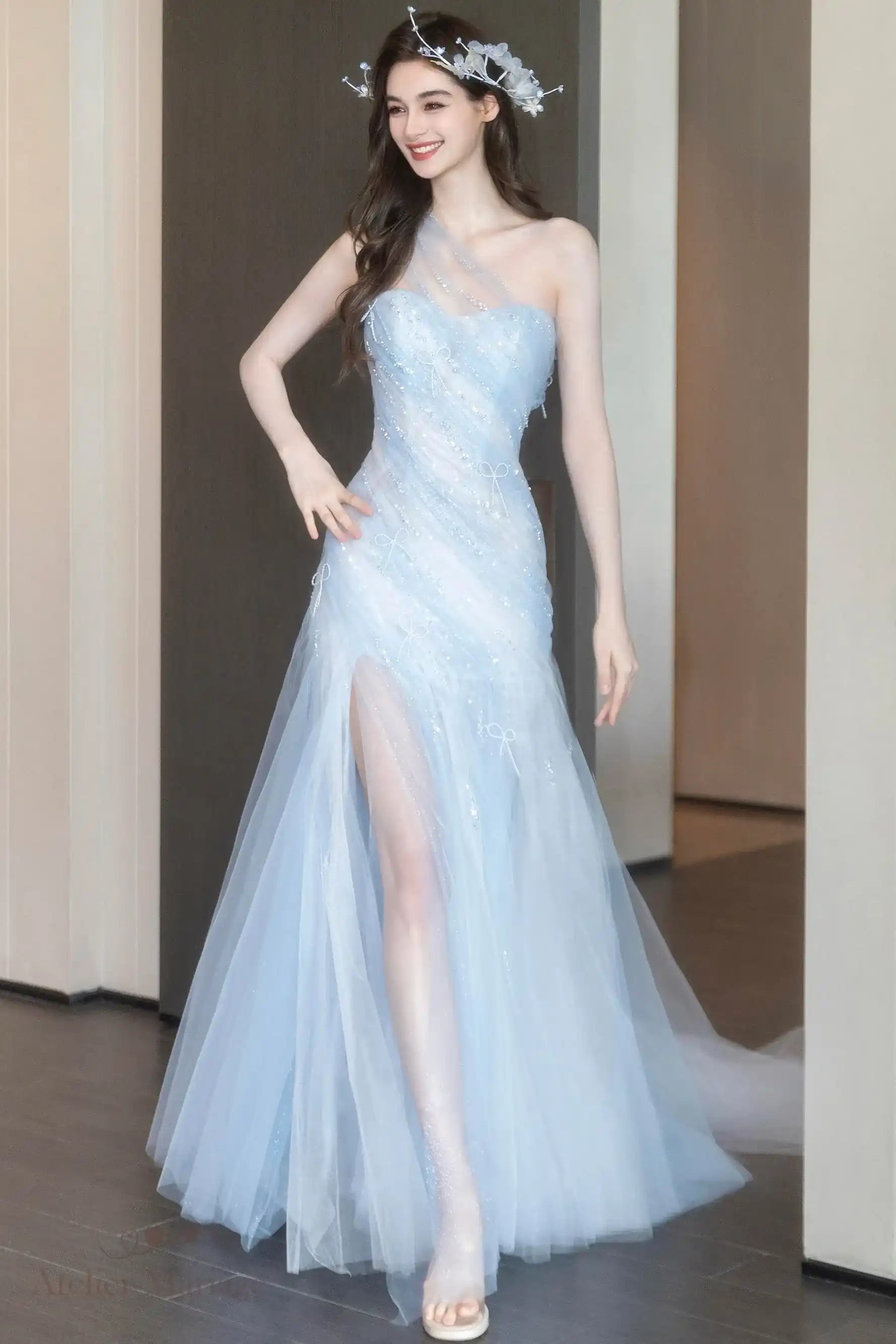 Robe de mariée coupe princesse fluide en tulle bleu brume posant en intérieur.