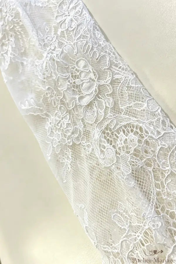 Vue rapprochée du travail de placement de dentelle artisanal pour une manche de mariée élégante.