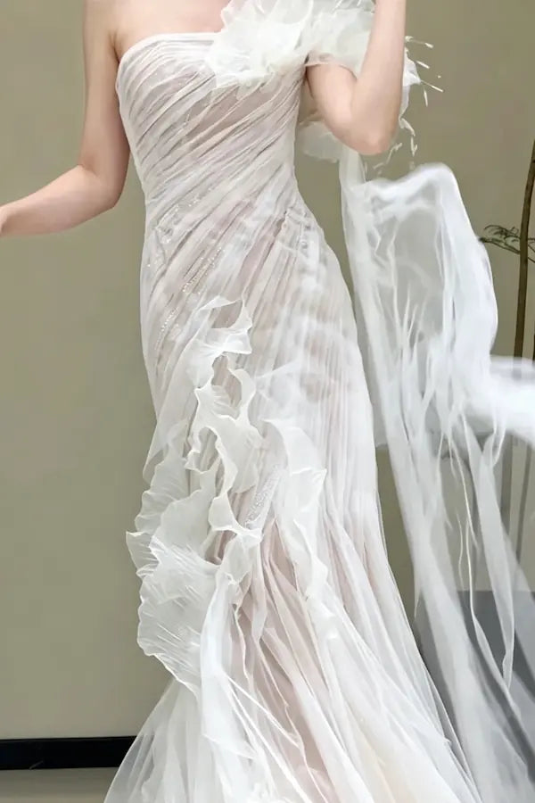 Mélange de textures luxueuses avec fleurs 3D et plumes vaporeuses sur une robe de mariée d'exception.