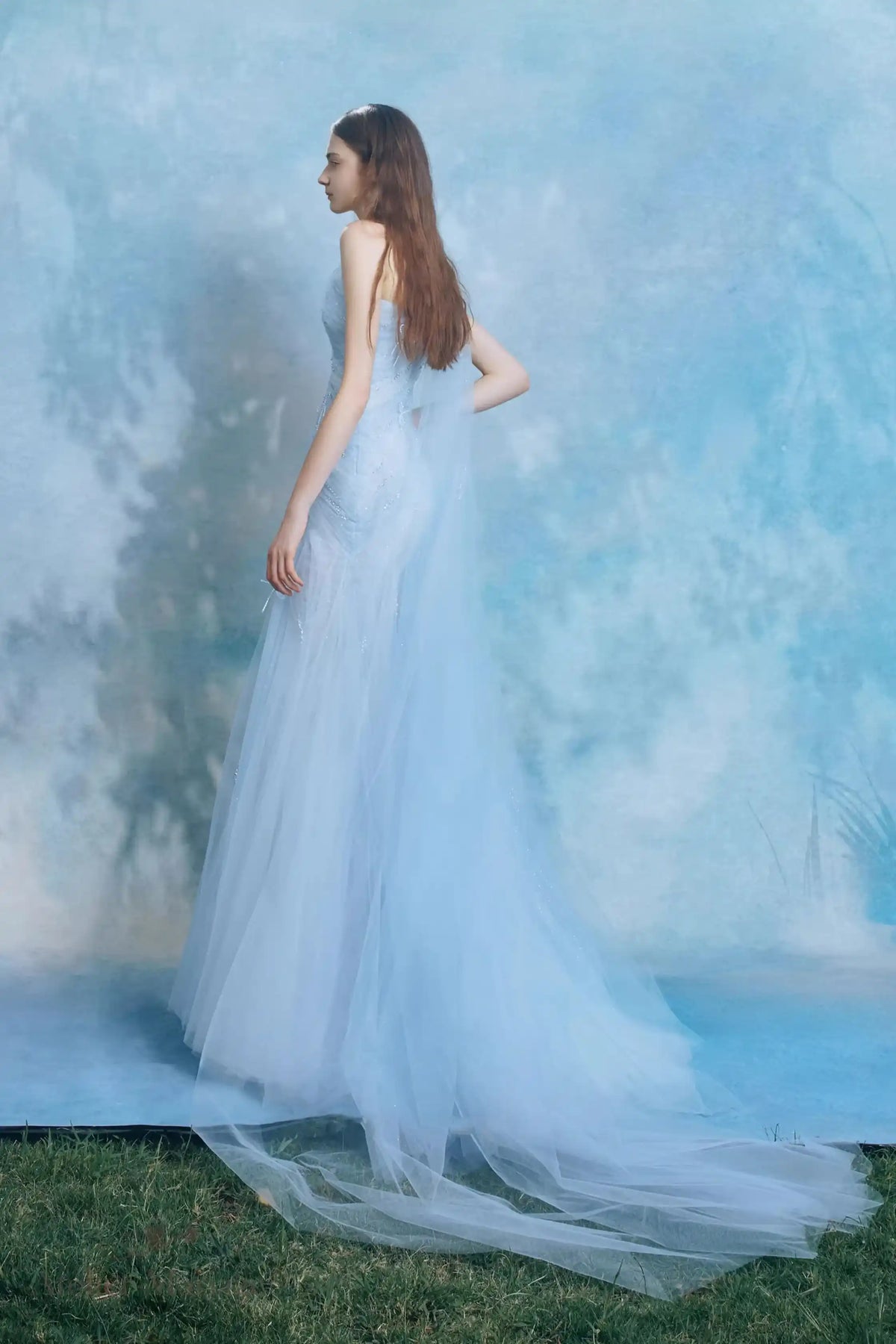 Mariée de profil montrant la délicate traîne de 30 cm de sa robe bleu brume.