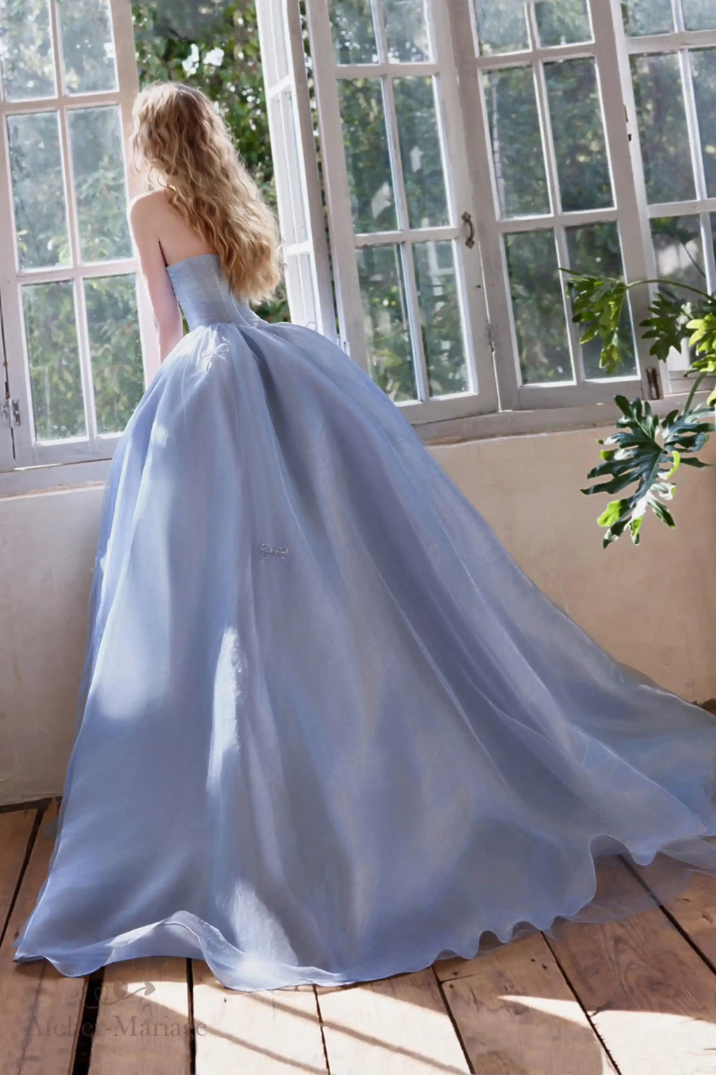 Vue de dos montrant la délicate traîne de 20 cm et le volume fluide de la robe de mariée bleue.