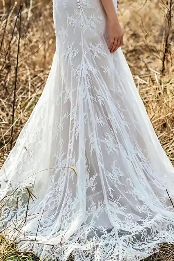 Vue de la traîne en dentelle délicate déposée sur l'herbe pour un mariage champêtre.