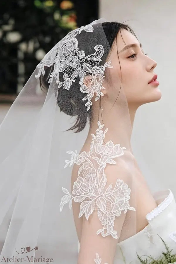 Vue de profil dramatique de la mariée, le voile long en dentelle guipure de 3 mètres crée une silhouette majestueus