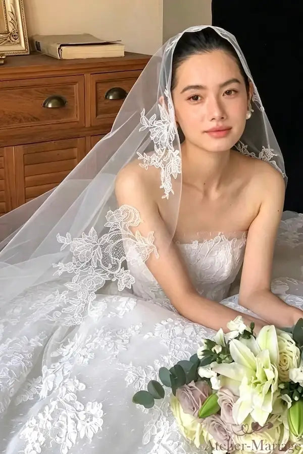 Portrait de douceur de la mariée portant le voile en dentelle de 3 mètres, expression paisible, boucles d'oreilles en perles