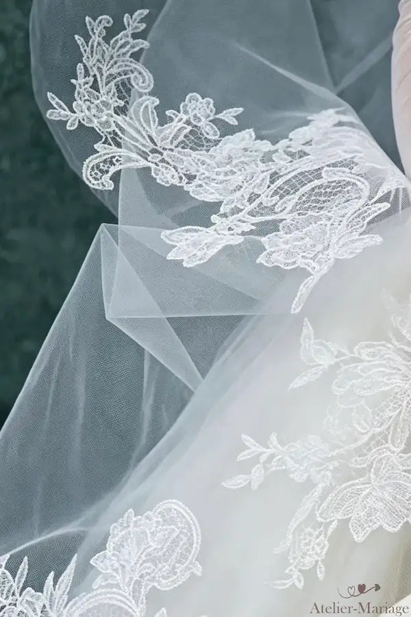 Détail de l'application de dentelle sur l'épaule, prolongeant le voile de 3m avec élégance