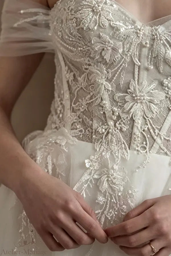Zoom sur les fleurs 3D et perles soulignant délicatement la taille.