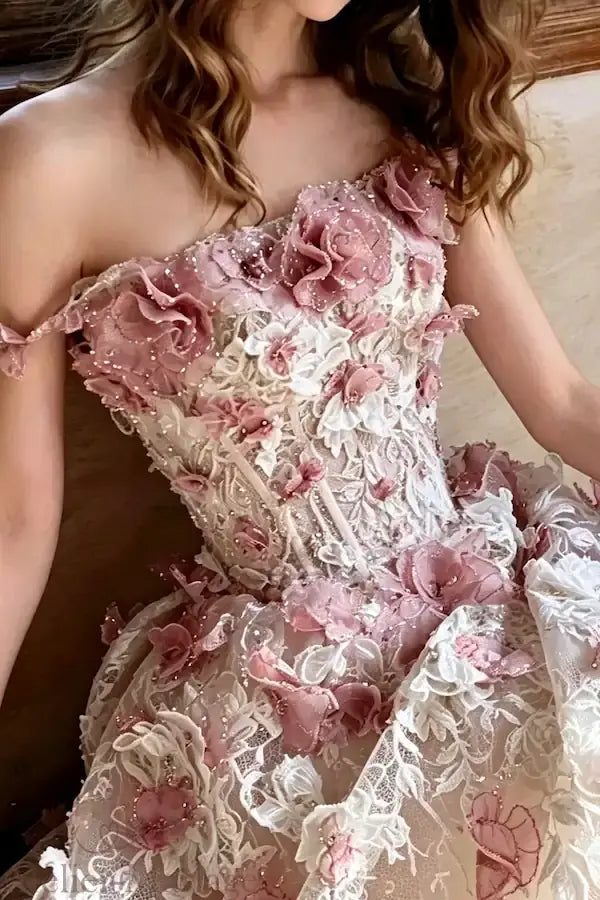 Zoom sur la broderie artisanale de fleurs 3D parsemant le tulle d'une robe blush